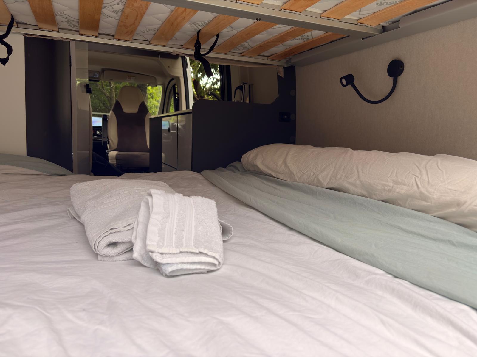 Cama amplia de la camper BiziVan con ropa de cama y toallas