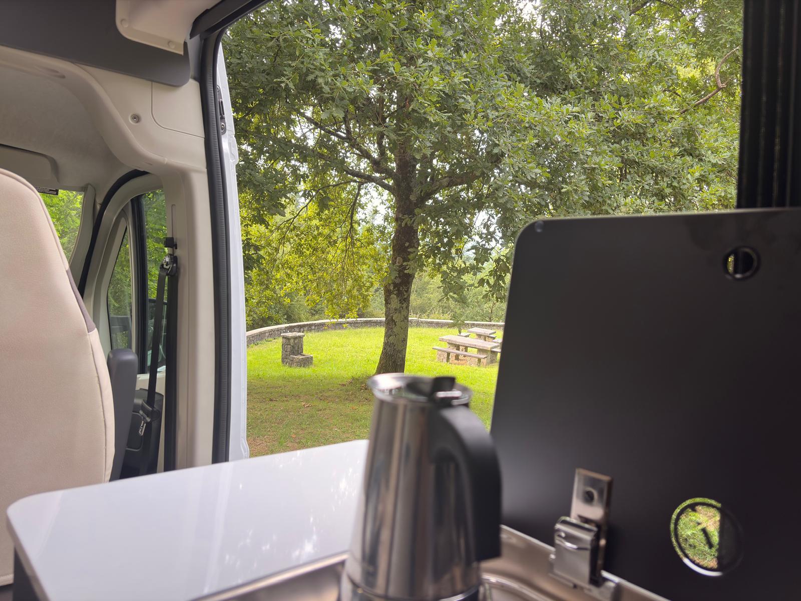 Cocina de la camper con hervidor y vistas a la naturaleza